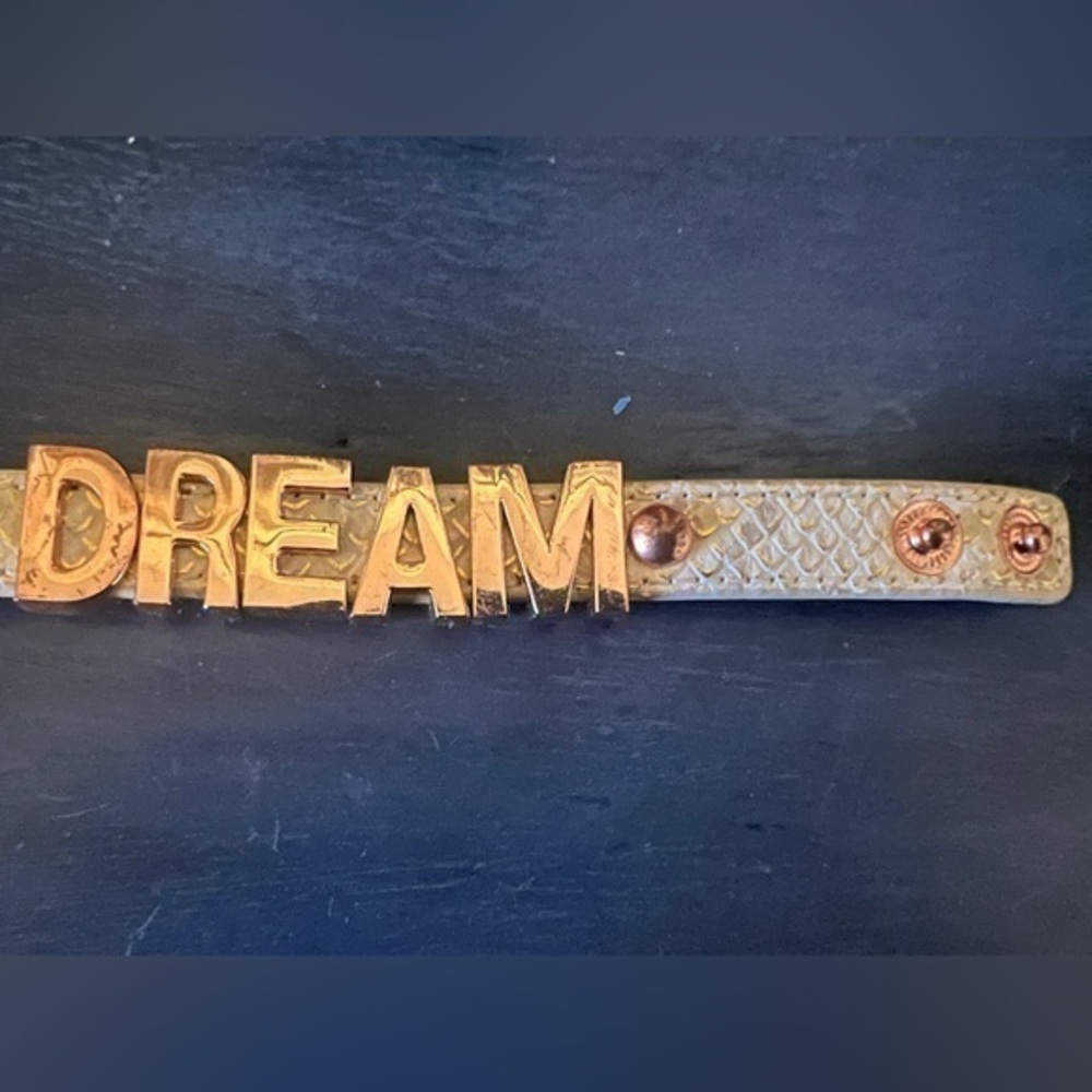 BCBGeneration DREAM bracelet. Snap closure. White & gold band w/gold lettering.